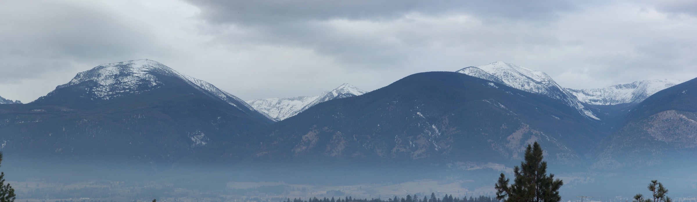 Snow-dusted Bitterroot Mountains above a hazy valley in western Montana.