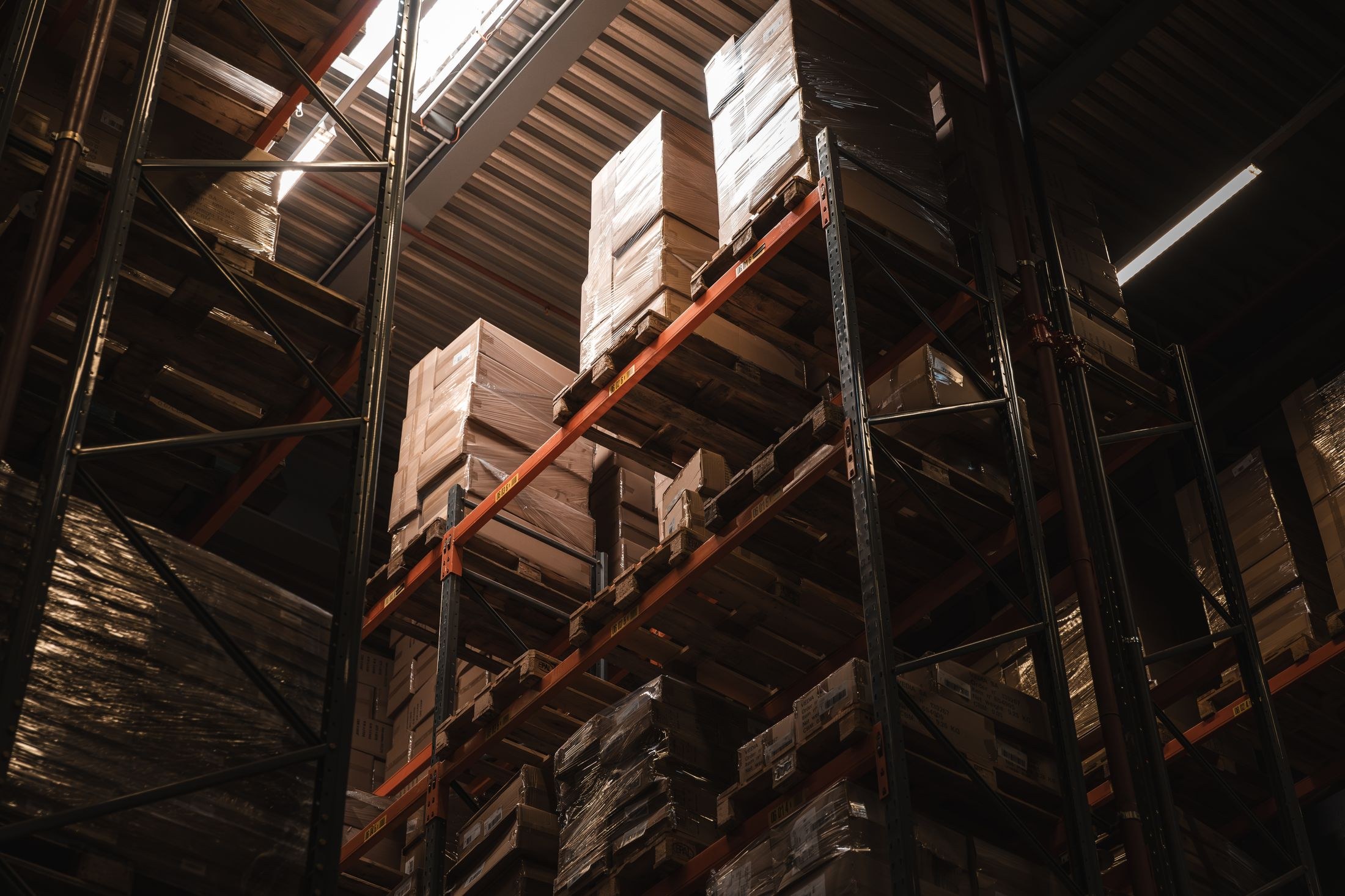 A warehouse interior with cardboard boxes stacked on tall storage shelves.